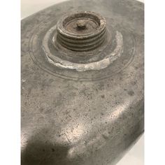 an old metal object is sitting on a white surface with the top part missing from it's base