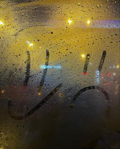 raindrops on the window and street lights in the back ground are seen at night