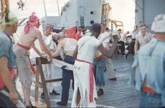 men in costumes are on the deck of a ship and one man is holding something