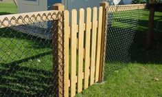 the fence is made of wood and has a chain link gate on top of it