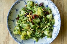 a bowl filled with broccoli and nuts on top of a wooden table