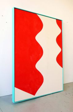 a large red and white painting sitting on top of a floor next to a wall