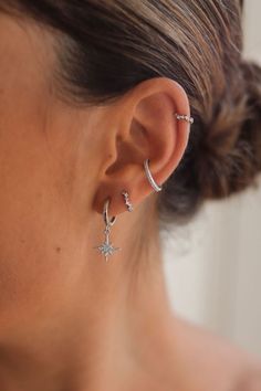 a close up of a woman's ear wearing two star and moon hoop earrings