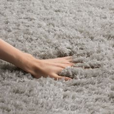 a person's hand on top of a gray rug