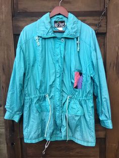 "Fantastic vintage 80's long teal windbreaker jacket. One small color block patch. Adjustable cinched waist. Zipper closure with a top and bottom button closing a flap over the zipper. Great vintage condition. By Hot Spices. Size medium. Measurements laying flat: Length: 31\" Sleeve length: 22\" Armpit to armpit: 24\"" Retro Hooded Cotton Windbreaker, Retro Multicolor Spring Windbreaker, 90s Multicolor Windbreaker For Outdoor, Retro Blue Long-sleeve Windbreaker, Vintage Multicolor Windbreaker With Pockets, Hot Spices, Favorite Sweater, Cinched Waist, Windbreaker Jacket