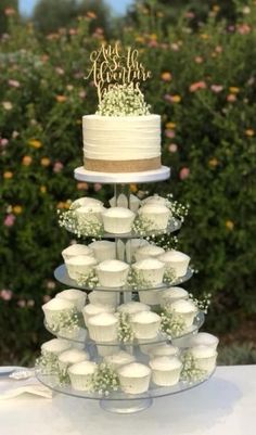 a tiered cake with cupcakes on the bottom is decorated with baby's breath flowers