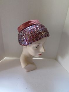 SALE! 10% OFF! Alluring vintage, mid century hat. The shape has a down-turned brim topped with a smaller crown in cinnamon tone satin. The brim is amazing--iridescent lavender color sequins cover the satin creating an unusual color combination as the satin shows through the sequins. For the crown, a 1" band circles it ending in a 4" bow at the back. The satin and sequins sit on a stiff platform. No maker label Size: 4 1/2" tall; 3 1/2" brim at front, 1" at back; 22" inner band circumference Cond Vintage Purple Hat With Short Brim, Vintage Short Brim Purple Hat, Pink Retro Party Hats, Vintage Purple Party Hat, Retro Brimmed Fascinator For Parties, Vintage Pink Costume Hats And Headpieces For Party, Vintage Pink Mini Hat With Curved Brim, Vintage Pink Party Hat And Headpiece, Pink Vintage Costume Hat For Parties