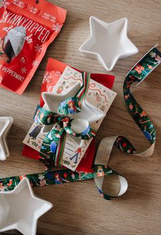 christmas wrapping supplies on a wooden table with star shaped dishes and ribbon tied around them