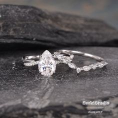 an engagement ring with a pear shaped cut diamond on top and leaves around the band