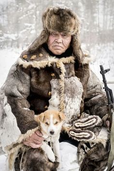 an old man sitting in the snow with his dog