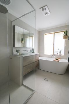 a bathroom with a tub, sink and large mirror in it's center area