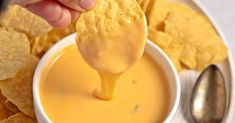 a person dipping cheese into a bowl of chips