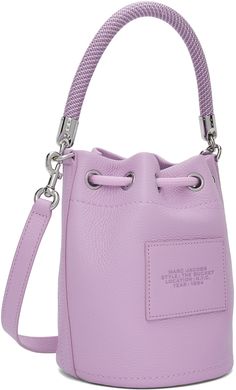 Grained leather shoulder bag in purple. · Braided rope carry handle · Adjustable and detachable crossbody strap · Logo and text embossed at face · Logo patch at back face · Cord-lock drawstring closure · Card slot at interior · Partial twill lining · H8.5 x W8 x D7 Supplier color: Wisteria Purple Travel Bag With Silver-tone Hardware, Purple Leather Bucket Bag, Purple Crossbody Bucket Bag With Adjustable Strap, Marc Jacobs Bucket Bag, Purple Braids, Face Logo, Braided Rope, Leather Bucket Bag, Leather Bucket