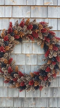 a wreath made out of pine cones and red berries is hanging on a brick wall