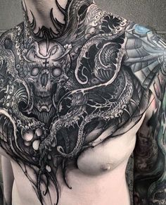 a man's chest covered in tattoos and an intricate dragon tattoo on his chest