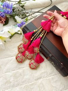 a pair of pink and gold tasseled earrings on top of a brown box