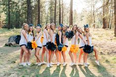 a group of young women standing next to each other in front of some pine trees