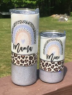 two personalized tumbles sitting on top of a wooden table in front of some grass