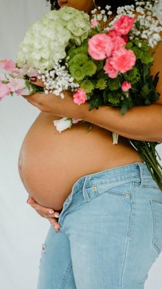 a pregnant woman holding flowers in her belly