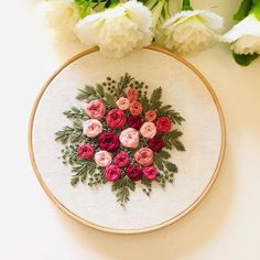 a close up of a embroidery on a white surface with flowers in the background and an embroidered hoop