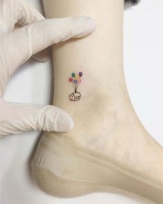 a person in white gloves holding up a small tattoo