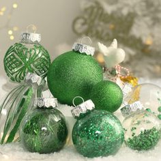 green christmas ornaments sitting on top of snow