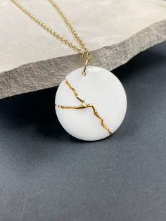 "Handmade porcelain kintsugi pendant necklace. Inspired by KINTSUGI. A perfect anniversary gift or encouragement gift. Kintsugi is a Japanese art of repairing broken pottery with gold. Ceramics once broken are glued back together with lacquer and finished with gold to bring beauty to what was once shattered. Kintsugi honors brokenness and challenges in life -- it celebrates beauty in the broken. This metaphor we can apply to ourselves. We can mend and transform what has broken us, and we can fin White Round Pendant Necklaces For Anniversary Gift, Minimalist White Jewelry For Anniversary, White Round Pendant Necklace For Anniversary, Minimalist White Jewelry For Anniversary Gift, Minimalist Handmade Necklace For Keepsake, Minimalist Handmade Keepsake Necklace, Minimalist White Keepsake Necklace, Kintsugi Necklace, Kintsugi Aesthetic