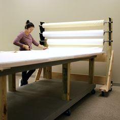 a woman is working on an assembly line in a room with white walls and carpeted flooring