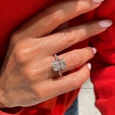 a woman's hand with a diamond ring on her left hand and a red sweater