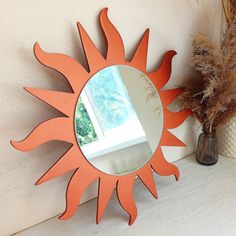 a mirror sitting on top of a table next to a vase