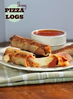 two pieces of pizza sitting on top of a white plate next to a bowl of sauce