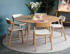 a round table with four chairs and a vase filled with flowers on top of it