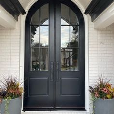 two planters with flowers are in front of a double door