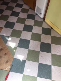 a kitchen floor with a checkered pattern on it and a red tool next to it