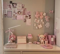 a white desk topped with lots of pink stuff animals and pictures on the wall behind it