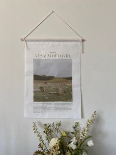 a vase filled with flowers sitting next to a wall hanging on a wall above a planter