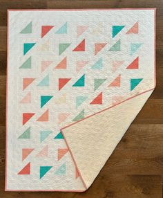 two quilts on top of each other, one with an orange and green triangle