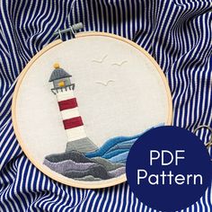 a cross stitch pattern with a lighthouse in the ocean on blue and white striped fabric