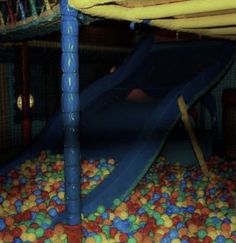 there is a blue slide in the ball pit with yellow and red balls on it