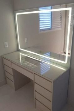 a white desk with a lighted mirror and drawers