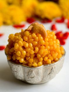 a small metal bowl filled with yellow and red corn kernels on top of a white table