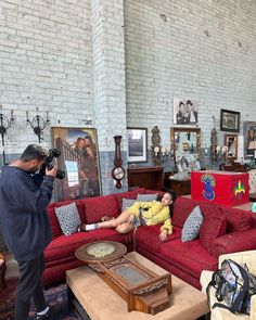 a man taking a photo of a woman laying on a red couch