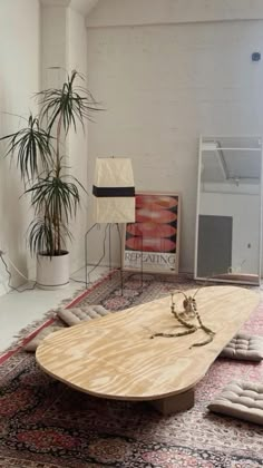 a large wooden table sitting on top of a rug next to a potted plant