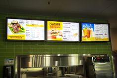 two menus are hanging on the wall above a restaurant counter and below a stainless steel refrigerator