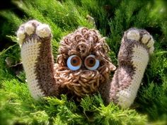 a close up of a stuffed animal in the grass with eyes on it's head