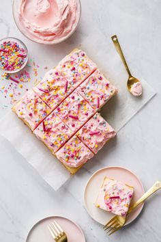 pink frosted cake with sprinkles and gold forks on white marble table