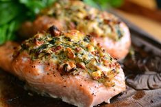 two salmon fillets with herbs and seasoning on them sitting on a cutting board