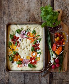 a pan filled with food sitting on top of a wooden table next to a bowl of veggies