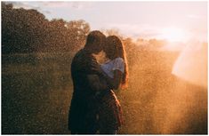 a man and woman kissing in front of the sun with water shooting from their backs