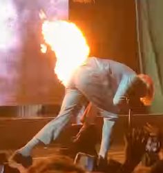 a man standing on top of a stage with fire in the air